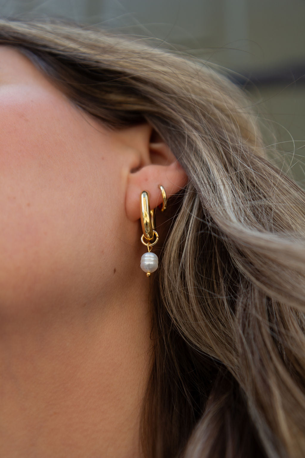 Boucles d'oreilles anneaux chunky ovales plaqués or avec perle Margot 8 sur une femme