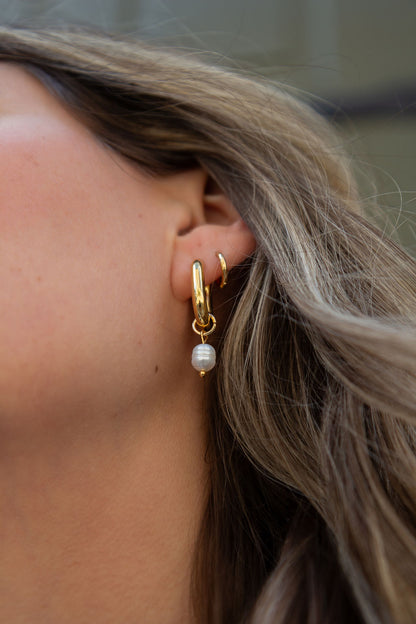 Boucles d'oreilles anneaux chunky ovales plaqués or avec perle Margot 8 sur une femme