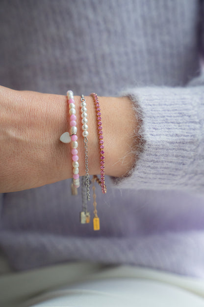 Bracelets colorés dans les tons de rose et perles blanches portés sur un poignet de femme