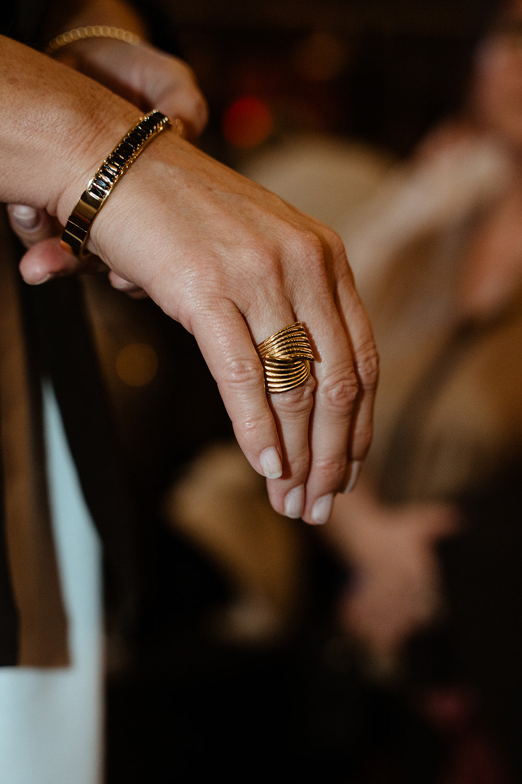 Bague maximaliste et bracelet cuff en acier inoxydable or style galmour portés sur une femme